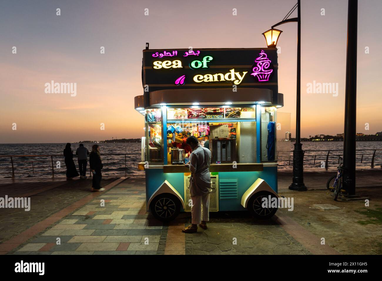 Jeddah, Arabia Saudita - gennaio 30 2023: Le persone si godono il crepuscolo presso la Corniche di al-Hamra con una bancarella di caramelle sul mare rosso in Arabia Saudita. Foto Stock