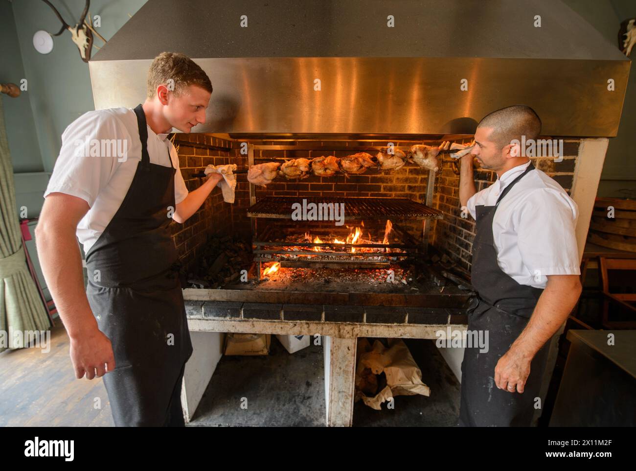Gli chef preparano pollo alla griglia per arrostire la domenica al Talbot Inn di Mells, Somerset, Regno Unito Foto Stock