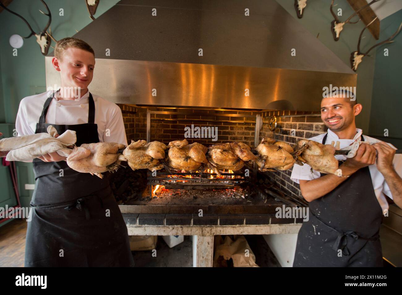 Gli chef preparano pollo alla griglia per arrostire la domenica al Talbot Inn di Mells, Somerset, Regno Unito Foto Stock