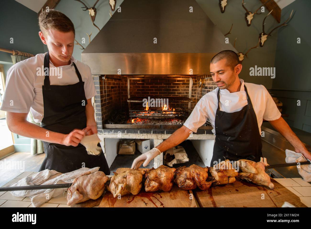 Gli chef preparano pollo alla griglia per arrostire la domenica al Talbot Inn di Mells, Somerset, Regno Unito Foto Stock