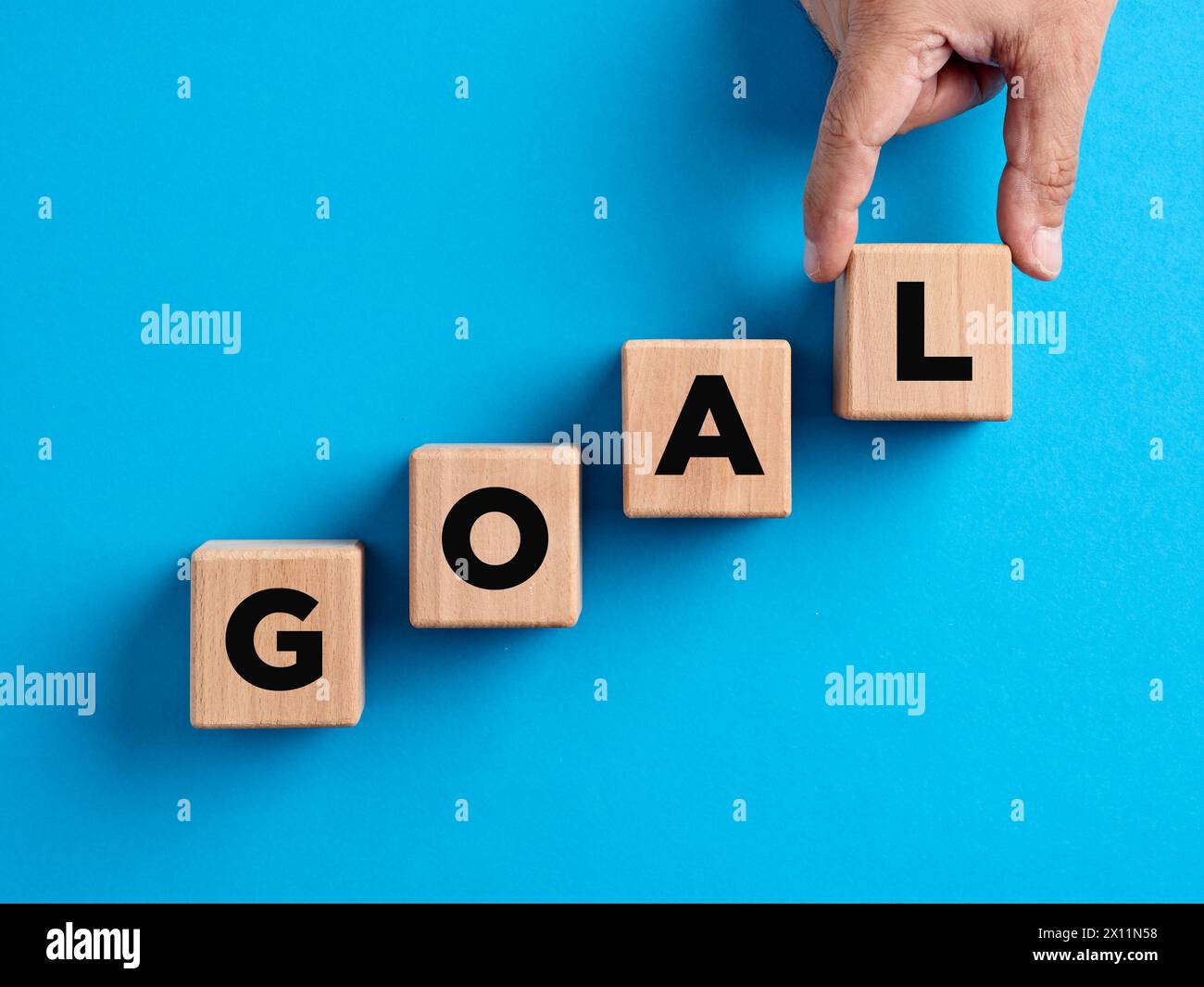 Raggiungimento degli obiettivi, definizione degli obiettivi, obiettivi aziendali, concetti di crescita e successo. La mano prepara i cubi di legno con la parola "goal". Foto Stock
