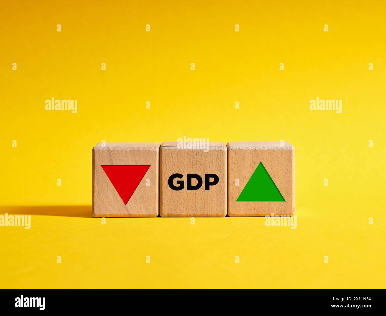 La variazione del PIL o della tendenza del prodotto interno lordo va verso il basso o verso l'alto. Cubi di legno con l'acronimo GDP e le frecce rivolte verso l'alto e verso il basso. Foto Stock