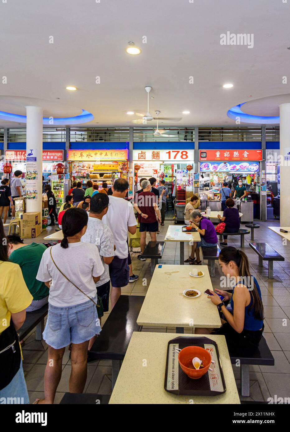 Persone in fila in un affollato Hawker Centre al mercato di Tiong Bahru nella tenuta di Tiong Bahru, Singapore Foto Stock