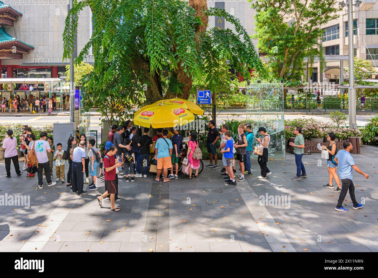 La gente si riunisce intorno a un carretto di gelati lungo Orchard Road a Singapore Foto Stock