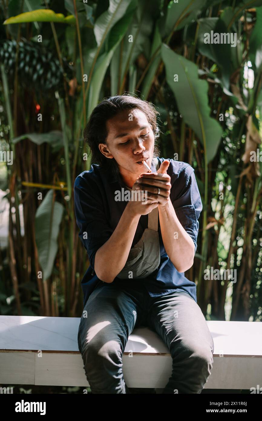 un uomo che stava bruciando la sigaretta in una zona di alberi ​​dense Foto Stock