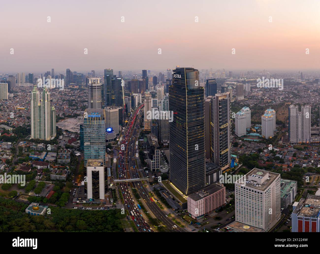 Giacarta, Indonesia - 16 luglio 2023: Vista aerea panoramica dello skyline del quartiere finanziario di Giacarta lungo l'affollato viale Sudirman al tramonto Foto Stock