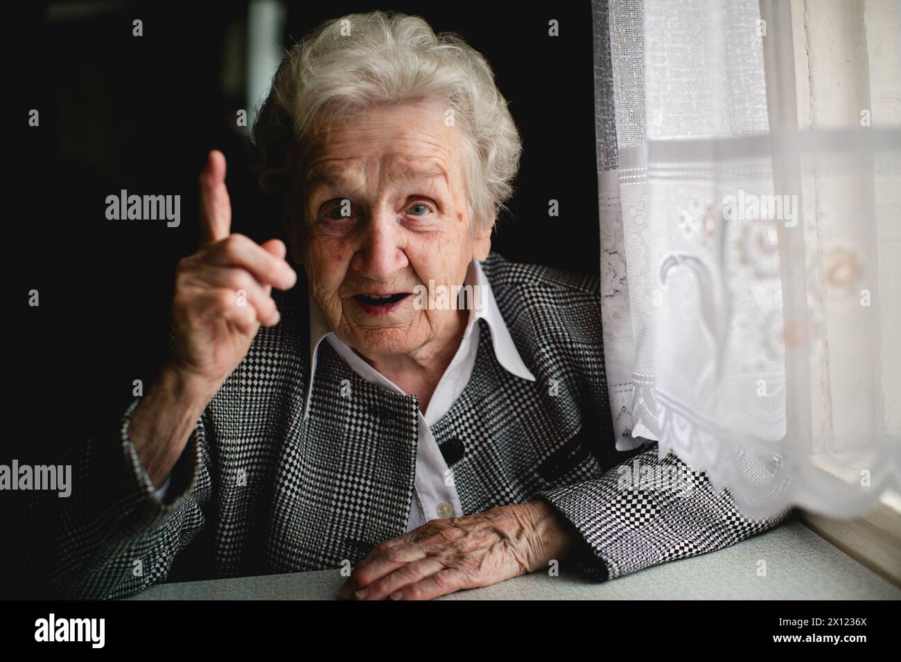 Fotografia di una donna matura con un dito indice significativamente sollevato. Foto Stock