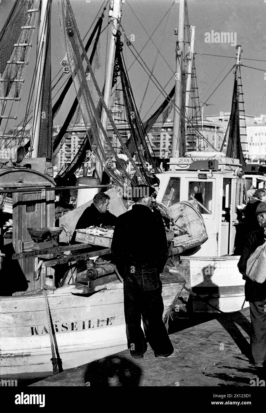 Pescatori che vendono pescato da vecchie barche da pesca in legno sul molo del Vieux Port o dal vecchio porto di pesca di Marsiglia Francia. Foto vintage o storiche monocromatiche o in bianco e nero c1960. Foto Stock