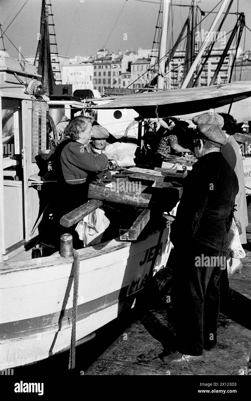 Pescatori che vendono pescato da vecchie barche da pesca in legno sul molo del Vieux Port o dal vecchio porto di pesca di Marsiglia Francia. Foto vintage o storiche monocromatiche o in bianco e nero c1960. Foto Stock