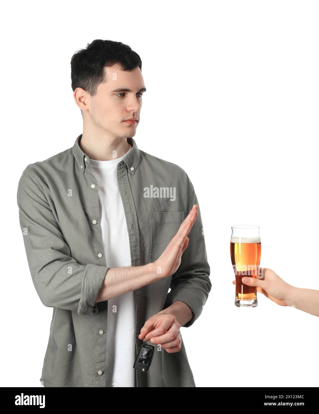 Uomo con le chiavi della macchina che rifiuta l'alcol mentre donna gli suggerisce birra su sfondo bianco, primo piano. Non bere e guidare Foto Stock