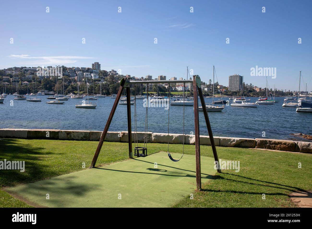 Parco giochi per bambini Sydney, Australia, con due altalene sulla spiaggia Forty Baskets e riserva con vista sugli yacht nel porto fino al sobborgo di Manly Beach Foto Stock