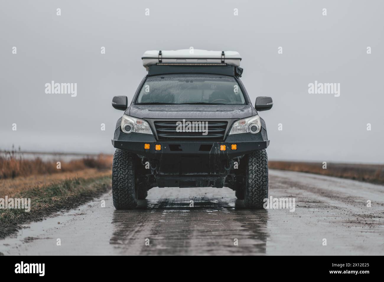 Veicolo fuoristrada grigio con tenda sul tetto su Wet Muddy Road Foto Stock