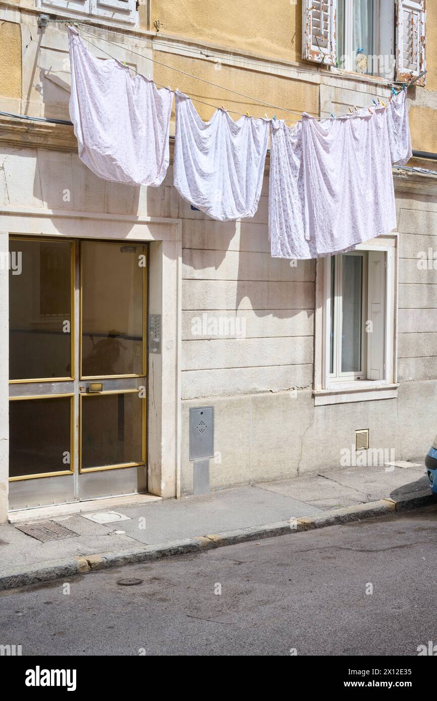 Facciata storica con abiti appesi su una linea di lavaggio Foto Stock