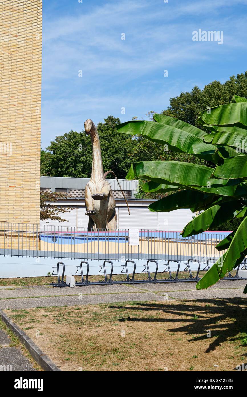 Dinosaurierfigur neben einem Haus mit Bananenbaum im Vordergrund Foto Stock