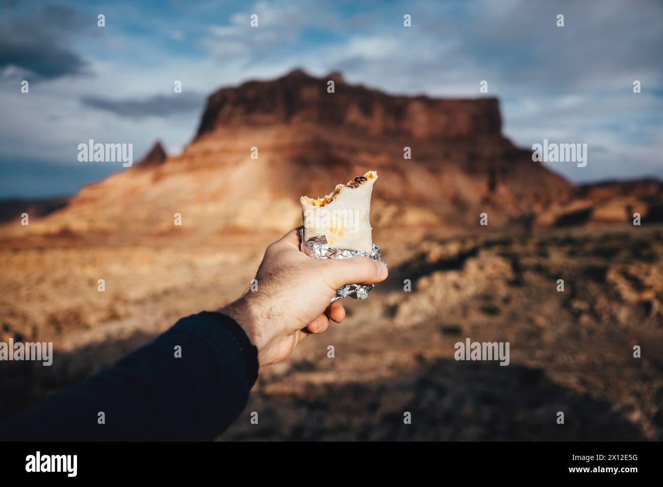 Tenere un burrito di fronte a una butte nel deserto Foto Stock