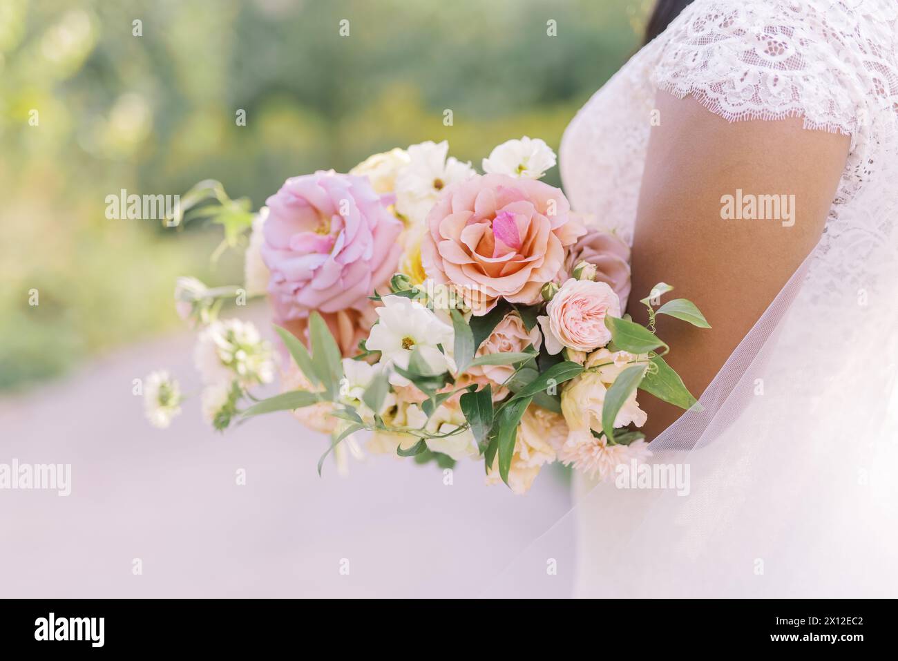 Bouquet nuziale rosa tenero tra le braccia della sposa Foto Stock