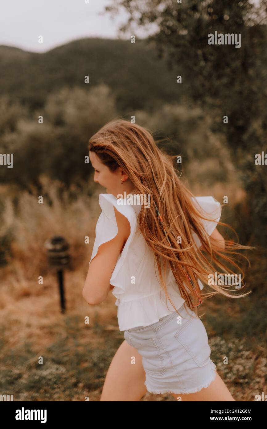 Joyful Teenage Girl Running Down Hill with a Smile Foto Stock