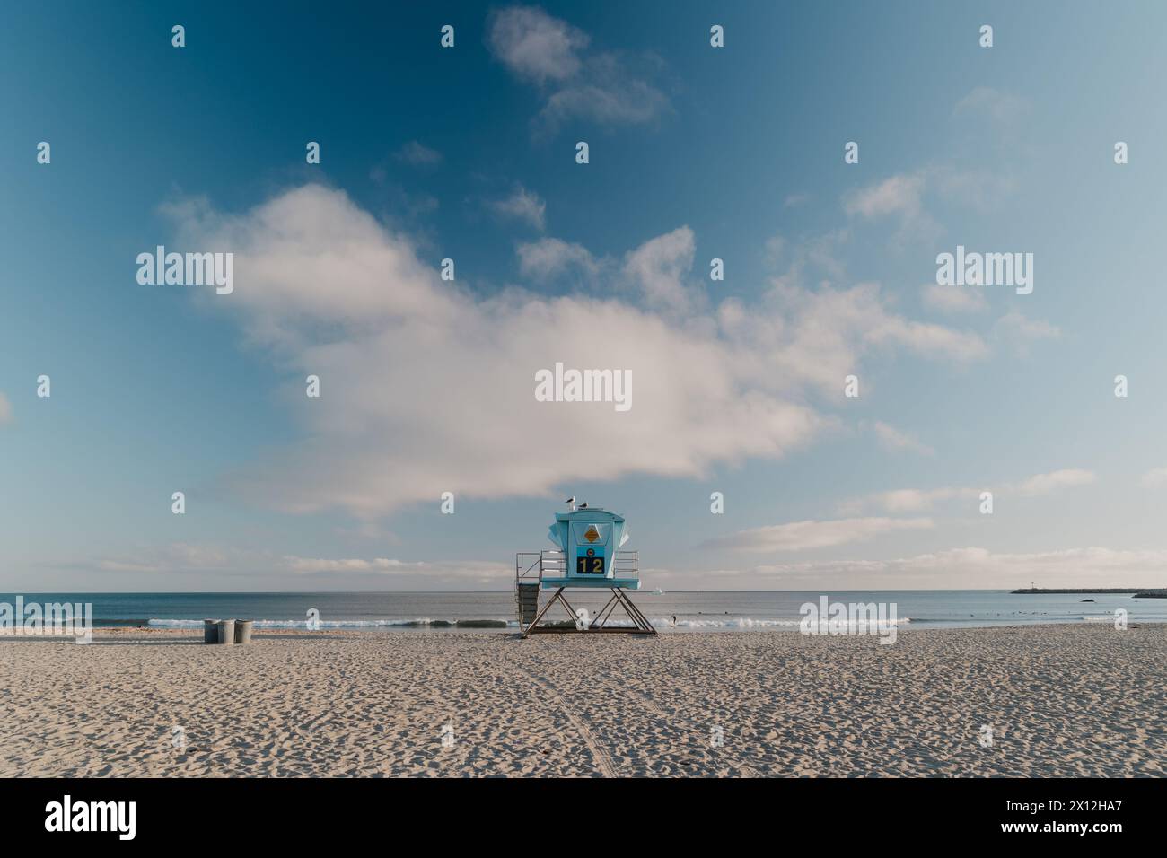 La torre statale del bagnino si trova sulla spiaggia vuota con i surfisti in acqua Foto Stock