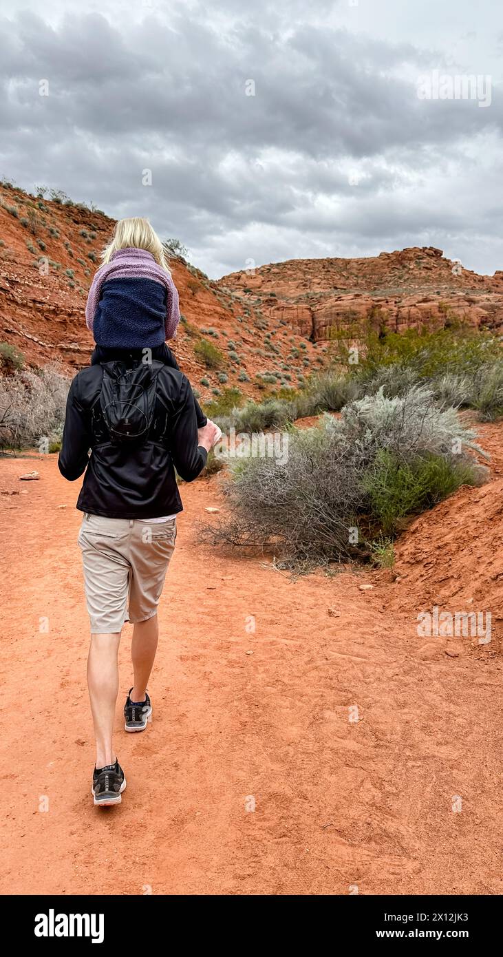 Padre con bambino su un tranquillo sentiero nel deserto sotto cieli nuvolosi Foto Stock