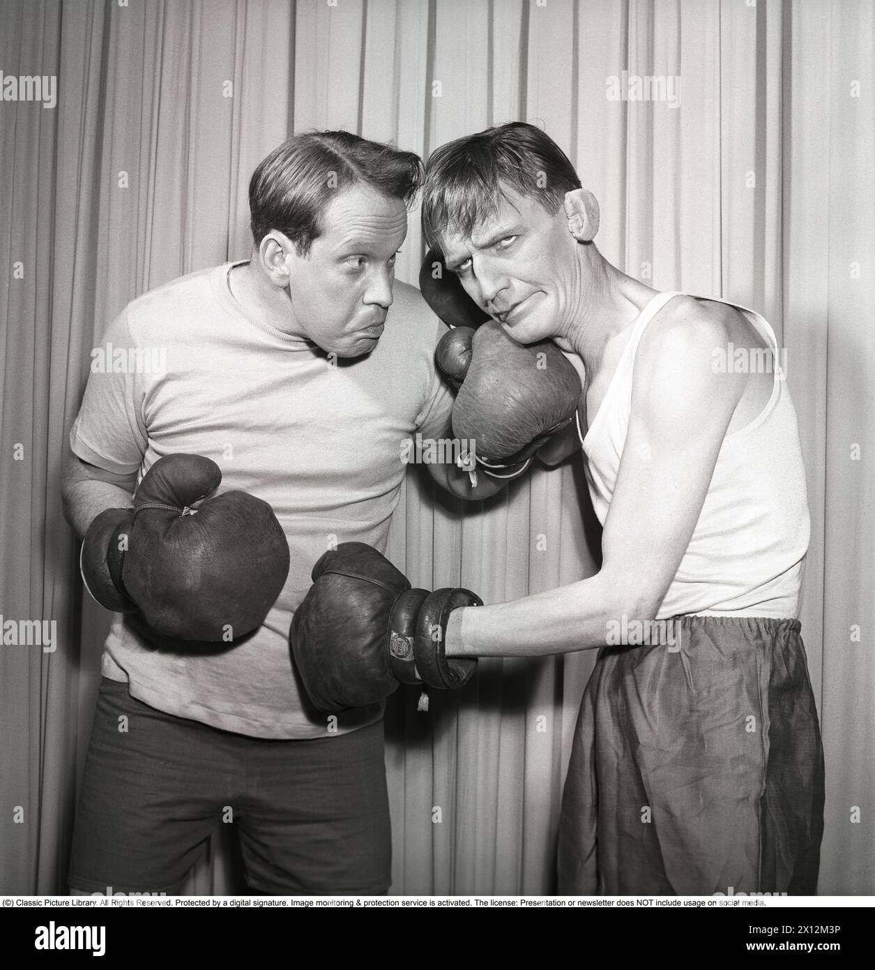 Divertimento al pugilato i due attori della rivista indossano abiti da palco catturati nel momento in cui si scontrano indossando guanti da boxe e lanciando pugni. Carl-Gustaf Lindstedt. 1921-1992. Attore svedese. Qui a sinistra nella rivista di Scalateatern 'Här håller vi hus' 1952. Sulla destra, Curt Löwgren. 1908-1966. Kristoffersson rif. BH36-9 Foto Stock