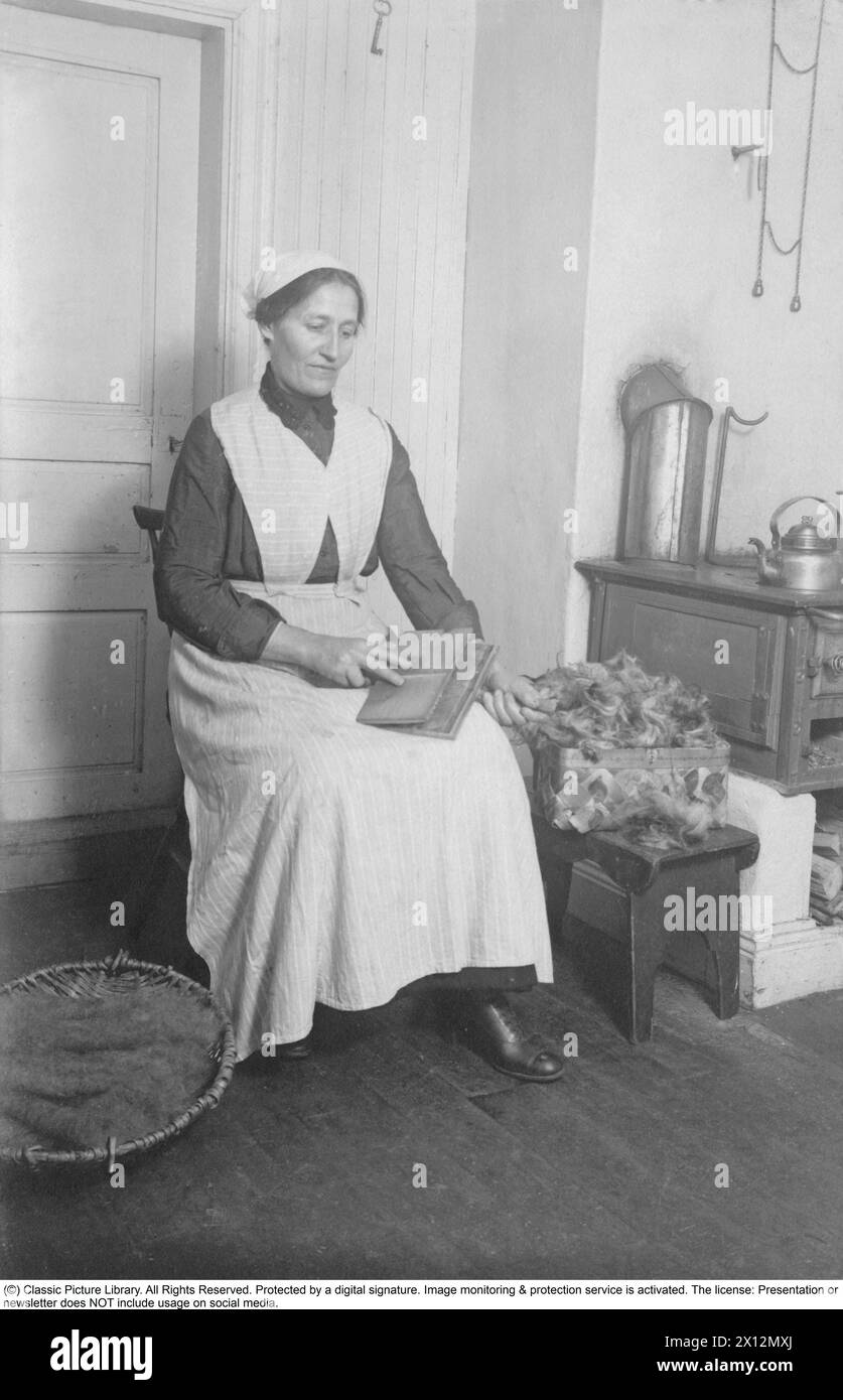 Anna Matilda Nordin, nata Bengtsson, visse nel 1874-1949 ed era sposata con il lavoratore Jan Olof Nordin (1869-1929). Vivevano a Bosjöfallet, un croft nella parrocchia di Rämmen, appena a nord di Lesjöfors in Värmland. Si siede in cucina a cartonare la lana. Una stufa a legna di ferro a destra per cucinare. anni '1930 Foto Stock