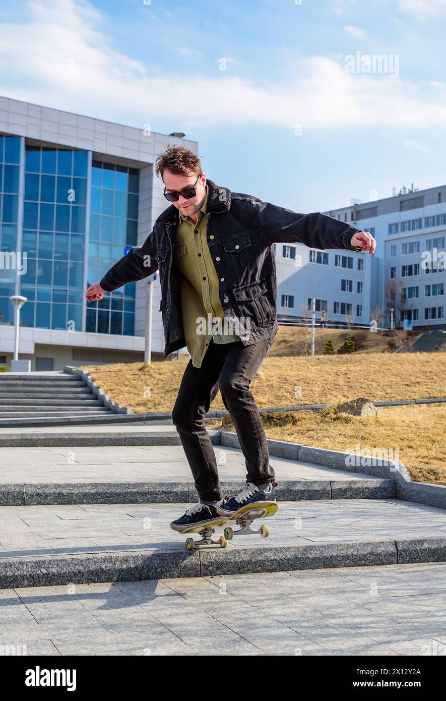 Giovane che cavalca uno skateboard facendo trucchi e salti Foto Stock