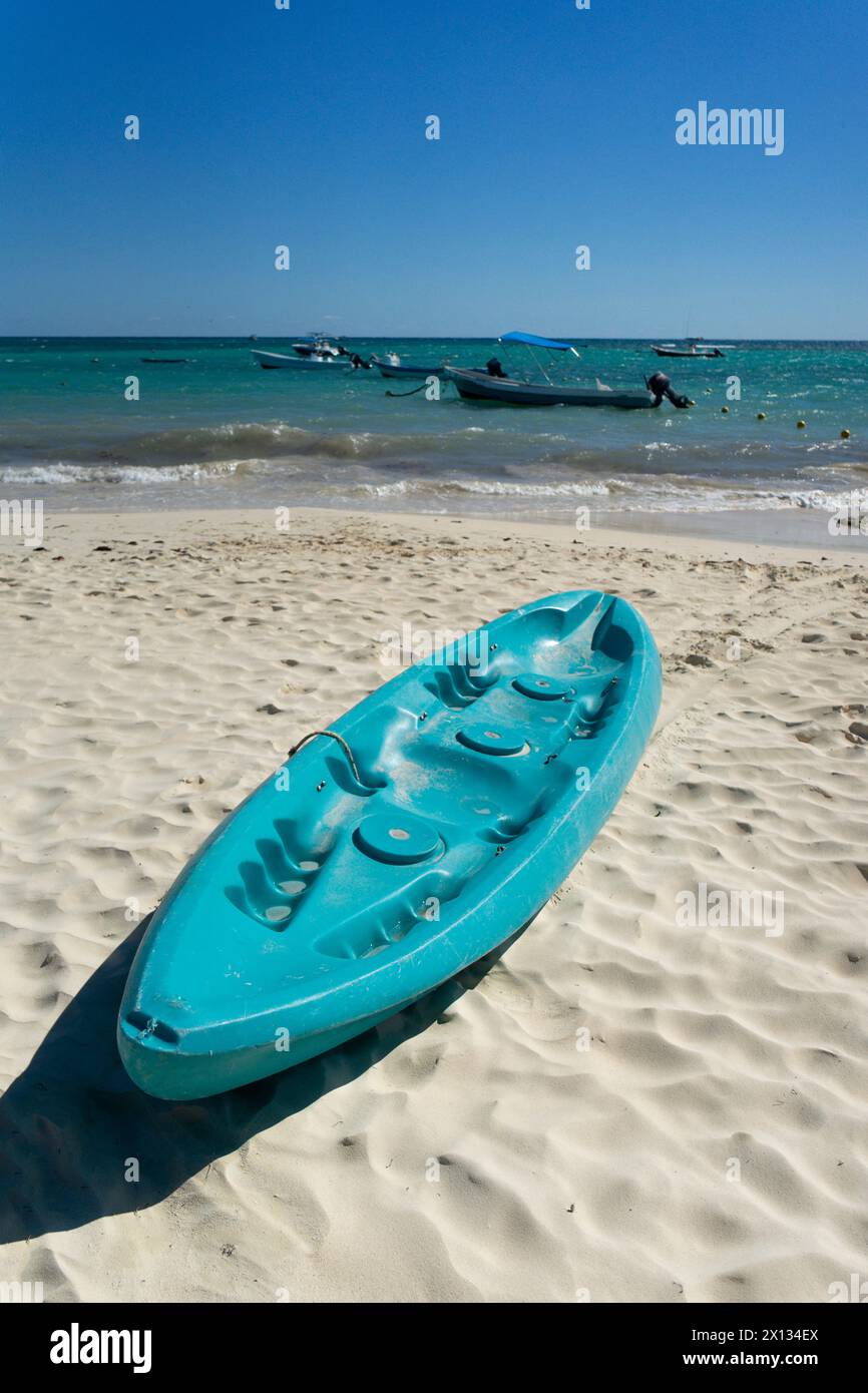 Spiaggia tropicale in Messico con kayak turchesi su sabbia bianca, cielo blu e mare calmo con barche sullo sfondo. Luogo ideale per vacanze sportive e Foto Stock