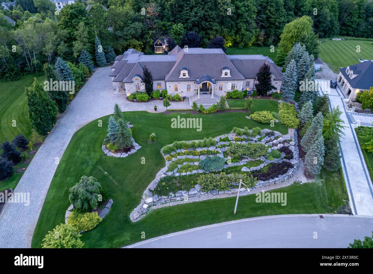 Scopri il fascino delle case di lusso da un milione di dollari in affascinanti paesaggi crepuscolari. Esplorate gli splendidi giardini e i giardini sul retro sotto la notte Foto Stock