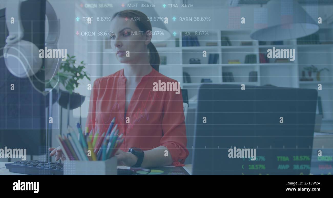 Una donna d'affari caucasica viene mostrata mentre lavora ad una moderna scrivania e guarda lo schermo di un computer Foto Stock