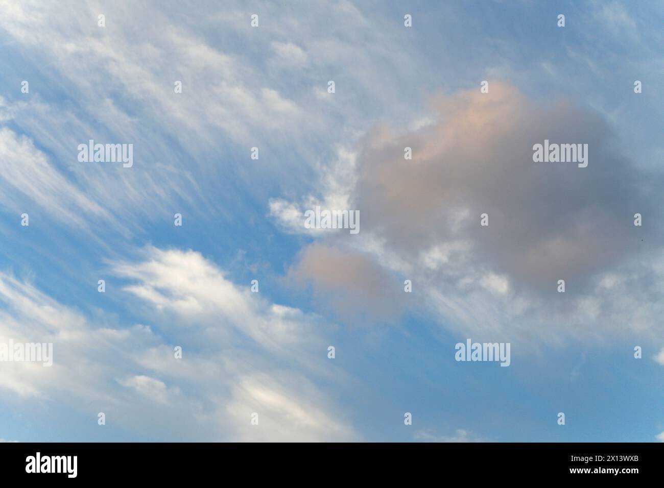 Un cielo tranquillo con morbide nuvole arancioni su uno sfondo blu chiaro Foto Stock