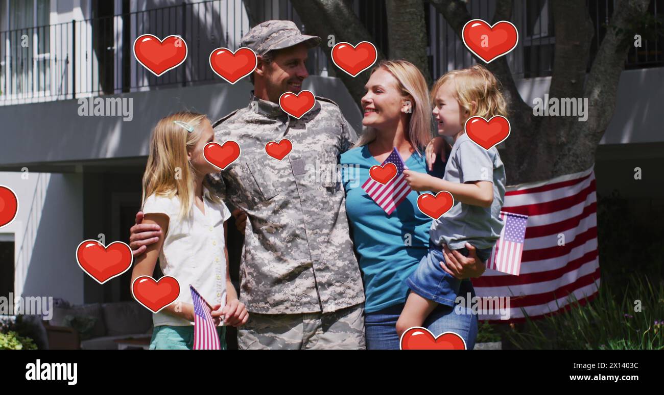 Immagine di cuori sorridenti soldato caucasico con famiglia con bandiere americane e abbracciante Foto Stock