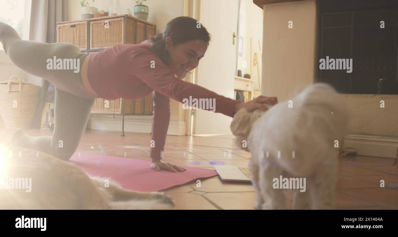 Un punto di luce contro una donna caucasica che fa yoga mentre gioca con il suo cane a casa Foto Stock