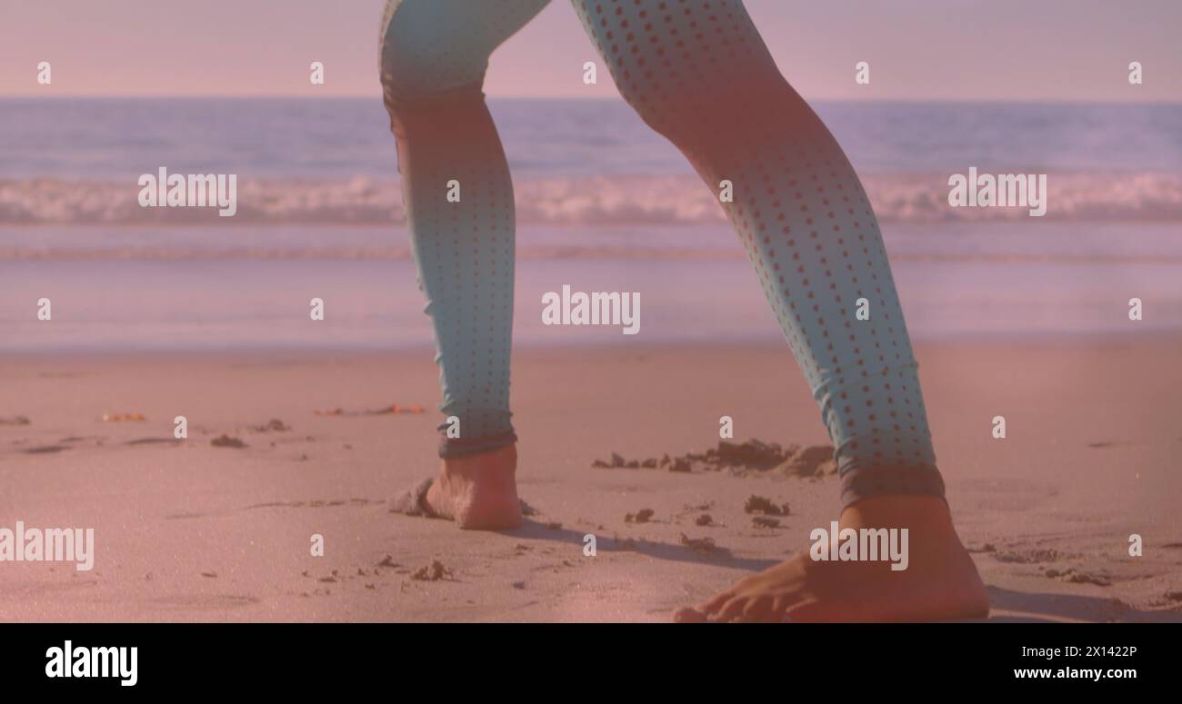 Immagine di luci sulle gambe di una donna caucasica che pratica yoga sulla spiaggia Foto Stock