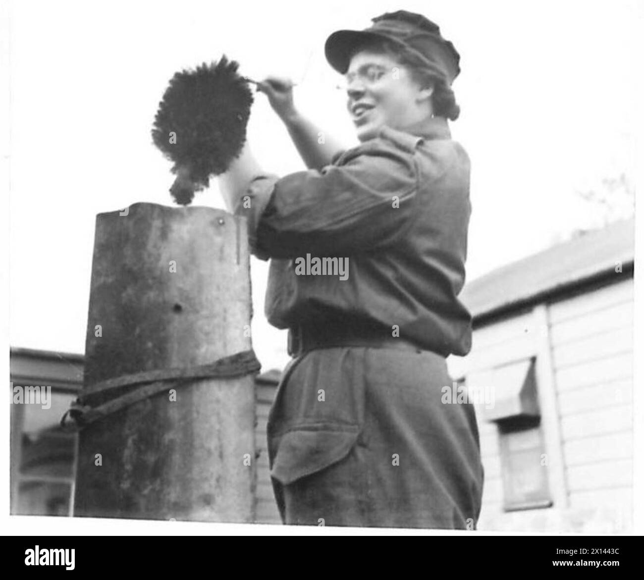 Presso una ATS Cookery School, un tirocinante pulisce una pila di camini della cucina da campo utilizzando una spazzola per canne fumarie, dimostrando le procedure di manutenzione. Foto Stock