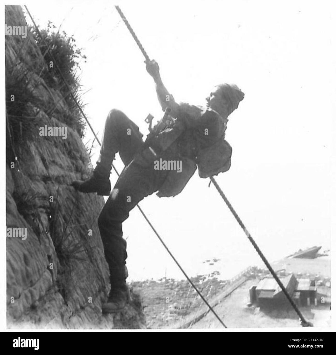 Il personale delle batterie di difesa costiera esegue esercizi di scalatura delle scogliere mentre trasporta armi per mantenere la forma fisica. Foto Stock