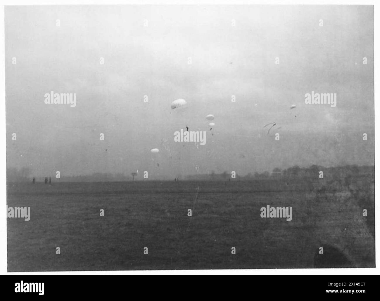 Le truppe di paracadutisti atterrano durante un'esercitazione militare, catturate su un vetro negativo. Foto Stock