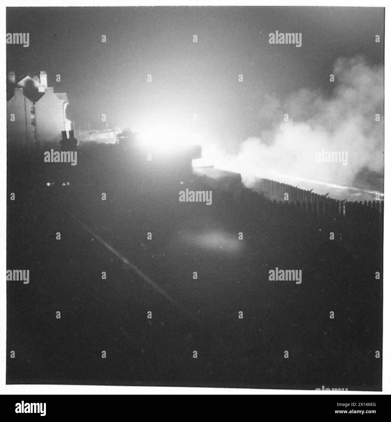 I corrispondenti di guerra osservano un cannone di difesa costiera del Coast Regiment R.A. sparare durante un esercizio notturno, mostrando operazioni di artiglieria. Foto Stock