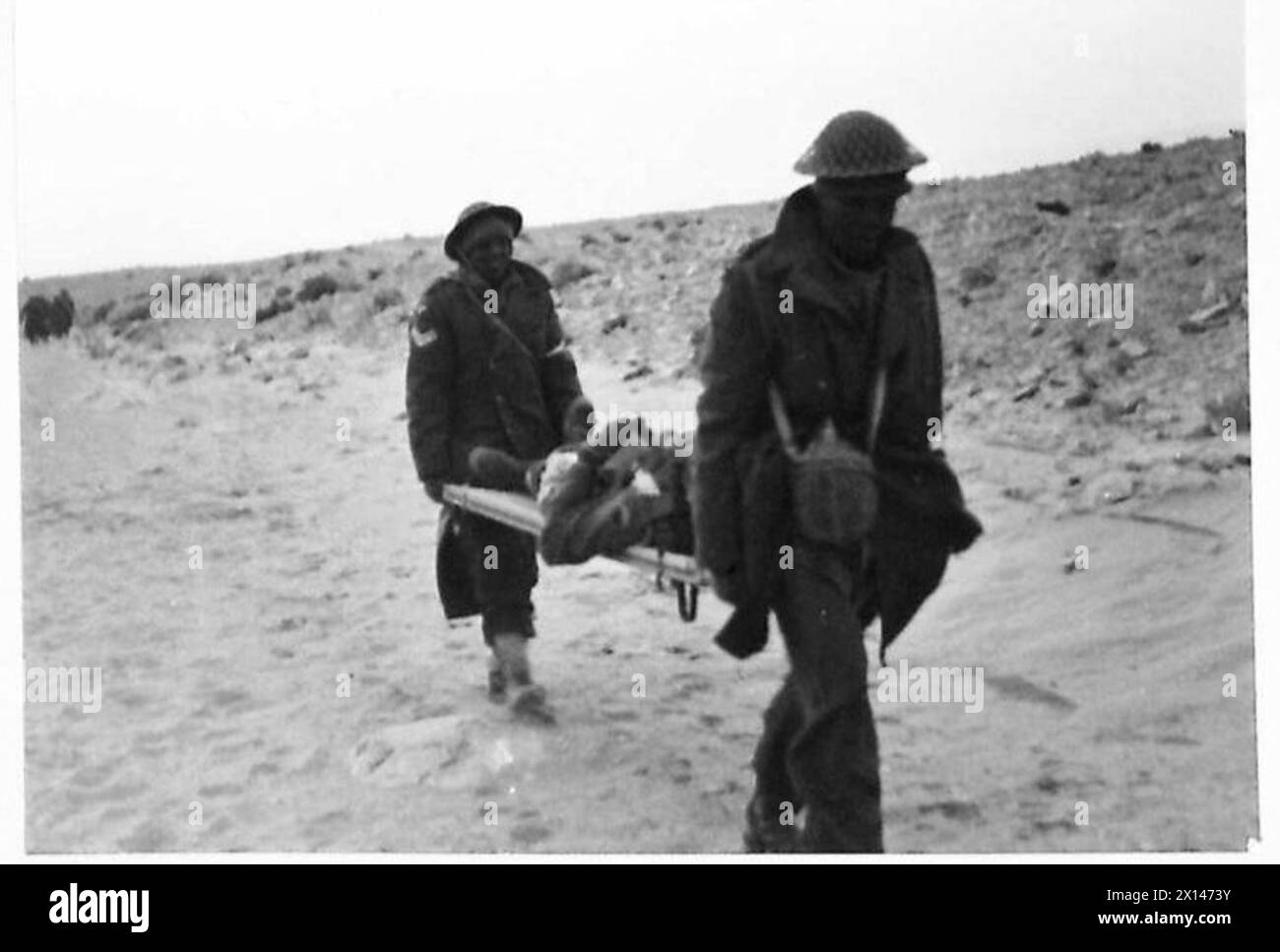 LE ULTIME FOTO DAL DESERTO occidentale - le truppe sudafricane si sono insinuate lungo i wadi verso Sollum durante la notte e hanno attaccato la città alle prime luci del giorno. Un uomo ferito portato dopo l'attacco dell'esercito britannico Foto Stock