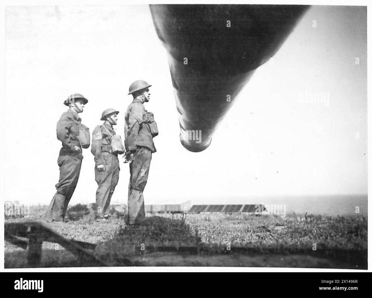 Tre membri dell'equipaggio posizionati vicino alla canna di un grande cannone d'artiglieria dell'esercito britannico. Foto Stock