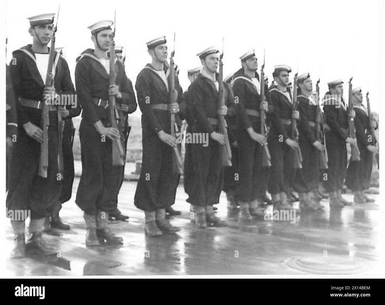 L'arcivescovo Damaskinos sale a bordo del suo lancio mentre l'equipaggio della nave greca Averof presenta le armi durante una revisione della flotta greca. Foto Stock