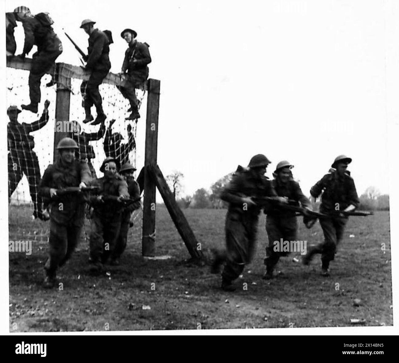 Le truppe che trasportavano fucili scalarono un ostacolo netto in un deposito di munizioni del comando occidentale, mentre i corrispondenti osservavano. Foto Stock