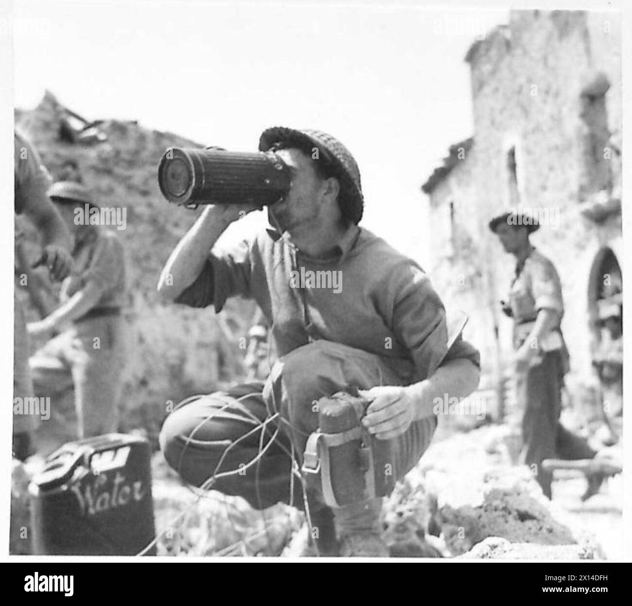 Un fanteria intorno a Cassino beve da un contenitore tedesco della maschera di gas in un punto d'acqua durante le operazioni sul campo, illustrando le routine dei soldati. Foto Stock