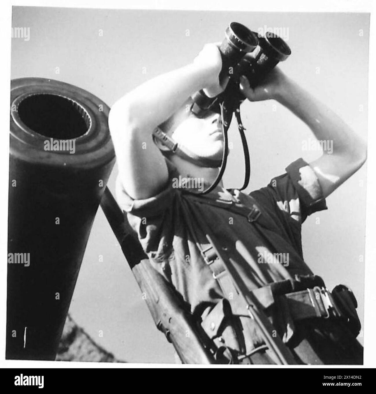 Un punto di osservazione di una batteria di difesa costiera scansiona l'orizzonte utilizzando un binocolo come parte dei compiti di sorveglianza. Foto Stock