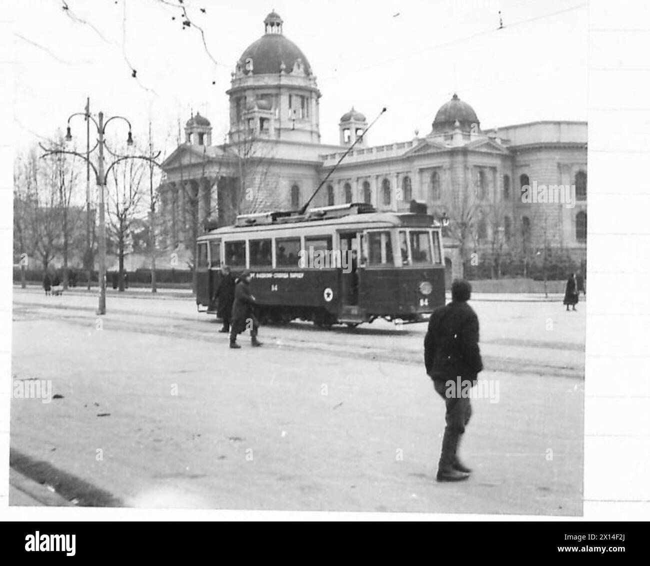 BELGRADETRANSPORT - il trasporto per i lavoratori della città corre alla periferia della città lungo la pista che passa davanti agli edifici del Parlamento, visti sullo sfondo. I lati del tram portano lo slogan "SMRT FASIZMU - SLOBODA NARODU" ("morte al fascismo - libertà al popolo") tra due Red Stars British Army Foto Stock