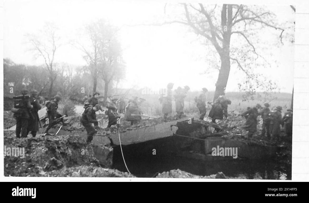 Una pattuglia del 10th Battalion, King's Liverpool Regiment, scorre attraverso i resti di un ponte distrutto dalle forze nemiche in ritirata durante le operazioni dell'esercito britannico, 21st Army Group. Foto Stock