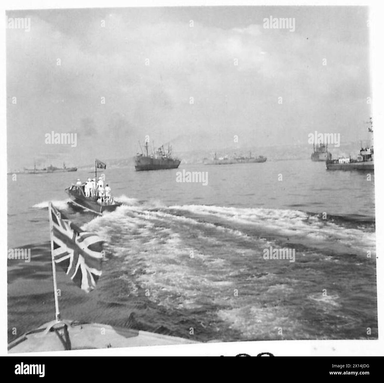 H.M. il Re viaggia a bordo della Royal Barge durante un tour del porto di Napoli, osservando le operazioni dell'esercito britannico e le strutture navali in Italia. Foto Stock