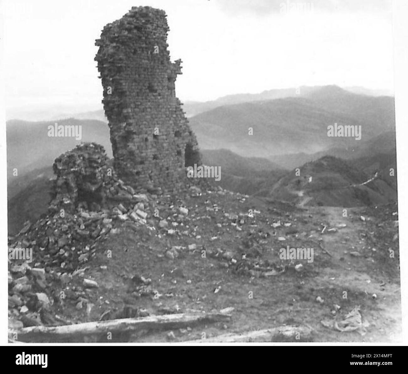 QUINTA ARMATA: MONTE BATTAGLIA - Sgt. W. Acton di Wellington, vicino a Liverpool, e Sgt. G. Pankhurst di Windsor, entrambi guardiani, esaminano un'arma trovata sul Monte Battaglia. Sullo sfondo sinistro si può vedere un proiettile scoppiare nelle attuali posizioni di prima linea del British Army Foto Stock