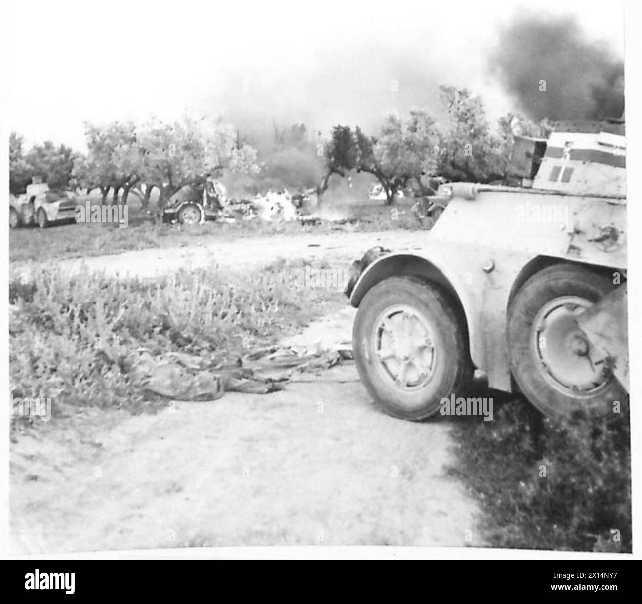 Durante le fasi finali della campagna nordafricana, nei pressi di Grombia si vedono bruciare autocarri e autocarri corazzati italiani, mostrando la distruzione del campo di battaglia. Foto Stock