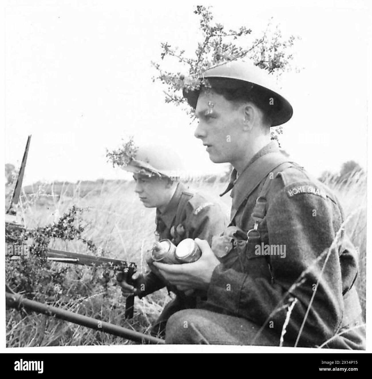 I membri della Home Guard utilizzano rami per mimetizzare i caschi in acciaio mentre si preparano per le operazioni sul campo, migliorando l'occultamento. Foto Stock