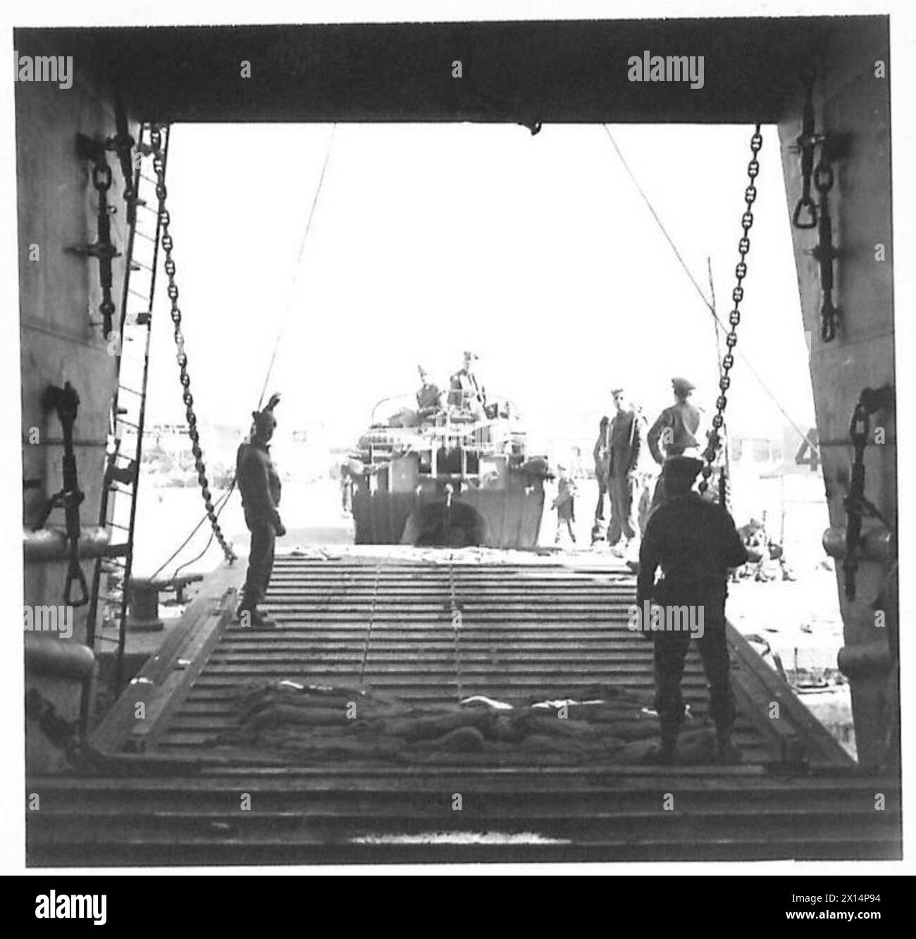 Veicoli anfibi alleati che salgono sulla rampa di un LST durante le prime operazioni di atterraggio a sud di Roma, osservati da un fante britannico in servizio di guardia, il British Army. Foto Stock